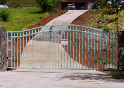 A weathered copper arched metal gate over a driveway.