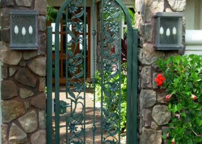 A green pedestrian gate with flowers and vines in metal.