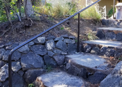 Custom built black hand rail down stone steps.