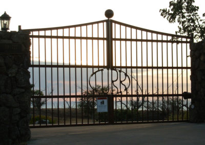 Fancy metal gate with surname and sunset behind.